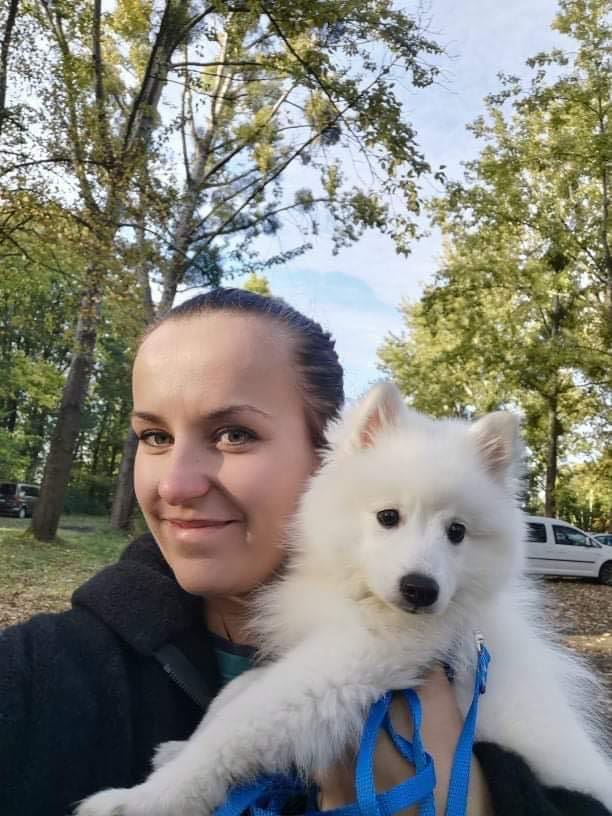 Karolina trzyma na rękach młodą białą suczkę szpica japońskiego Sayuri